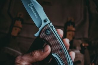 a hand holding an open tactical folding knife blade in full view