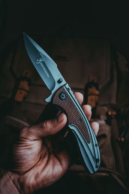 a hand holding an open tactical folding knife blade in full view