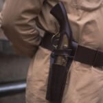 close up of a pistol carried in a holster on a waist belt