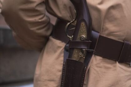 Close-up of a pistol carried in a holster on a waist belt