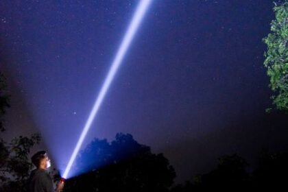 Bright flashlight beam projected into the night sky showing long-range throw