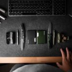 everyday carry tools laid out on a dark desk beside a keyboard