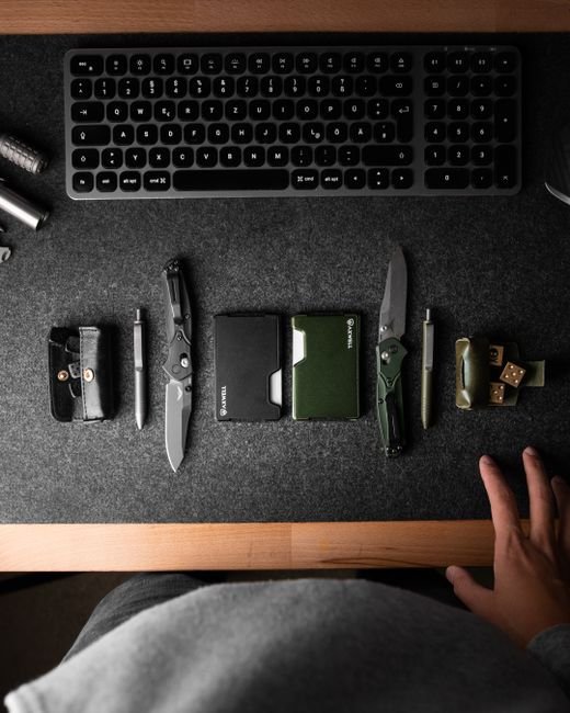 everyday carry tools laid out on a dark desk beside a keyboard