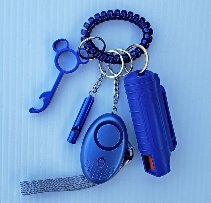 pepper spray canister on a keychain alongside a personal safety whistle