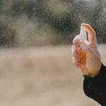 pexelsphoto4127602 edc deals person spraying from a handheld defensive spray canister outdoors