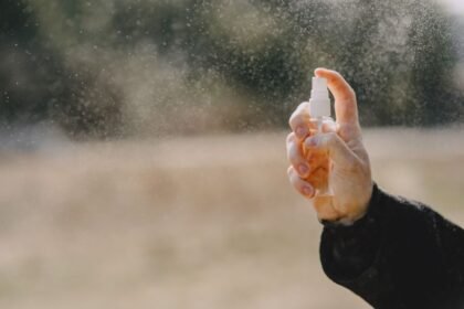 Person spraying from a handheld defensive spray canister outdoors
