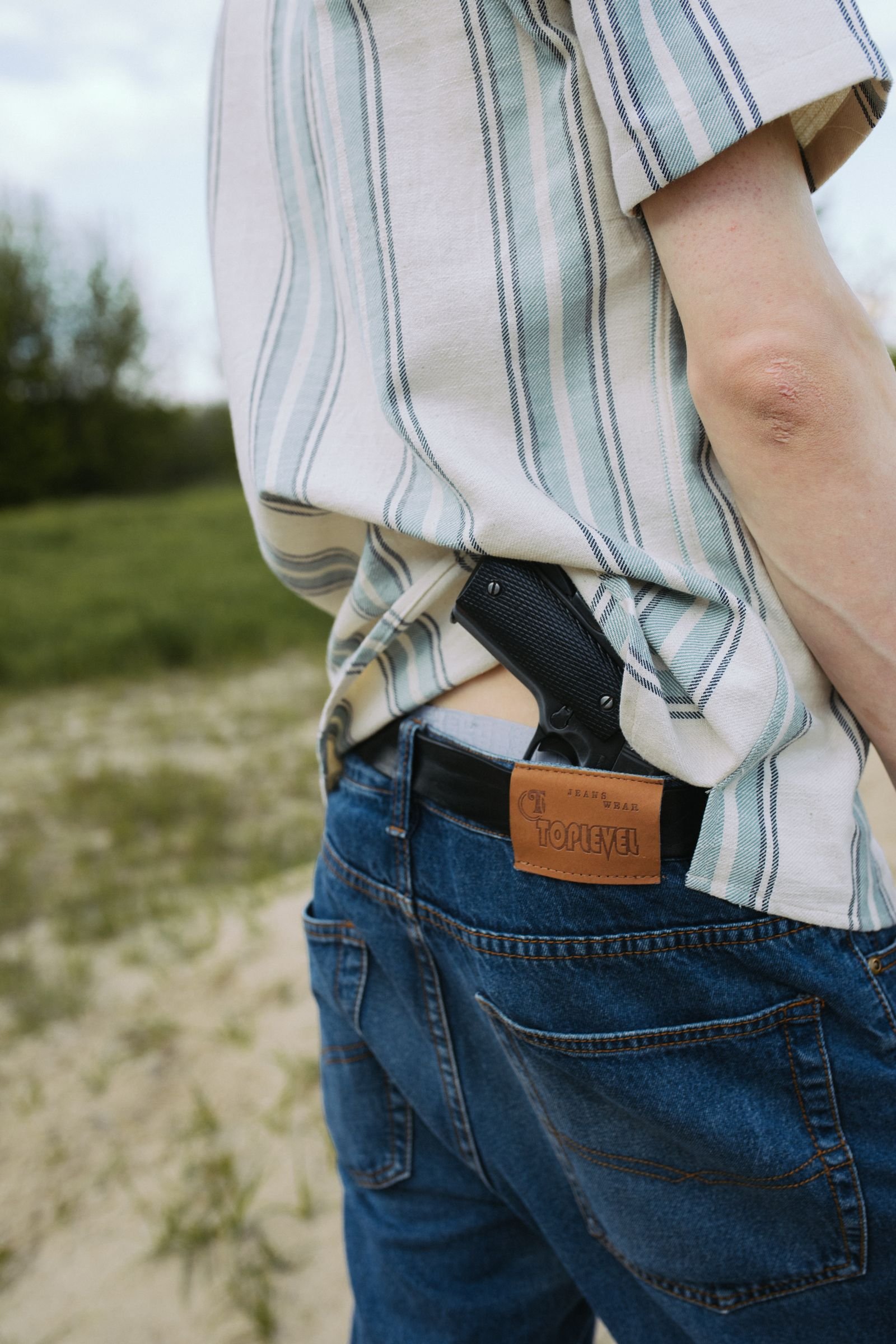pistol carried in a waistband holster under an untucked shirt showing how clothing conceals printing