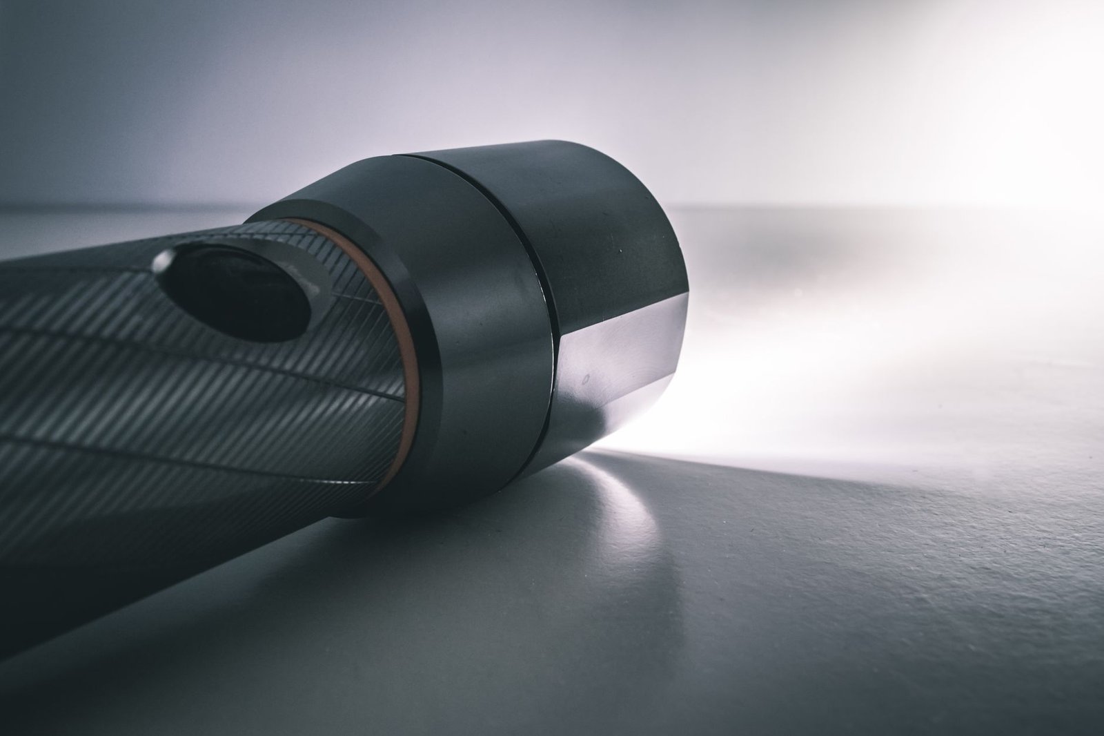 close up of a black camera lens lying on a white surface with soft light to the right