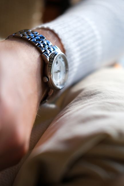 A silver analog wristwatch on a wrist, shown from above