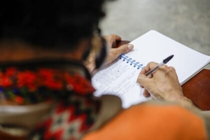 Writing in a spiral notebook with a ballpoint pen, a quick-drying choice for left-handed writers
