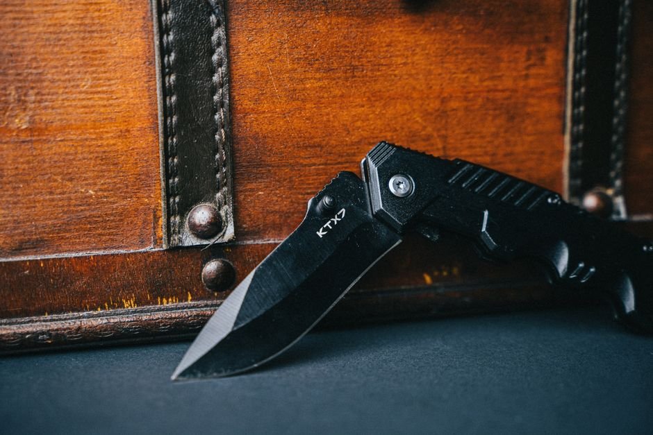Close-up of a black folding knife showing the full length of its edge