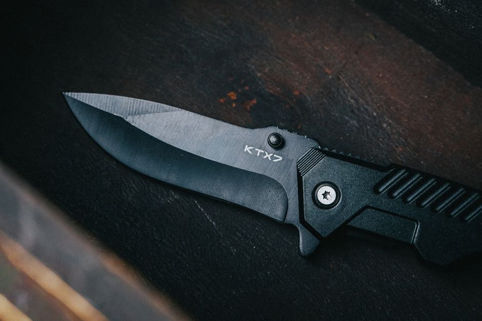 A black folding knife with a broad, grippable handle