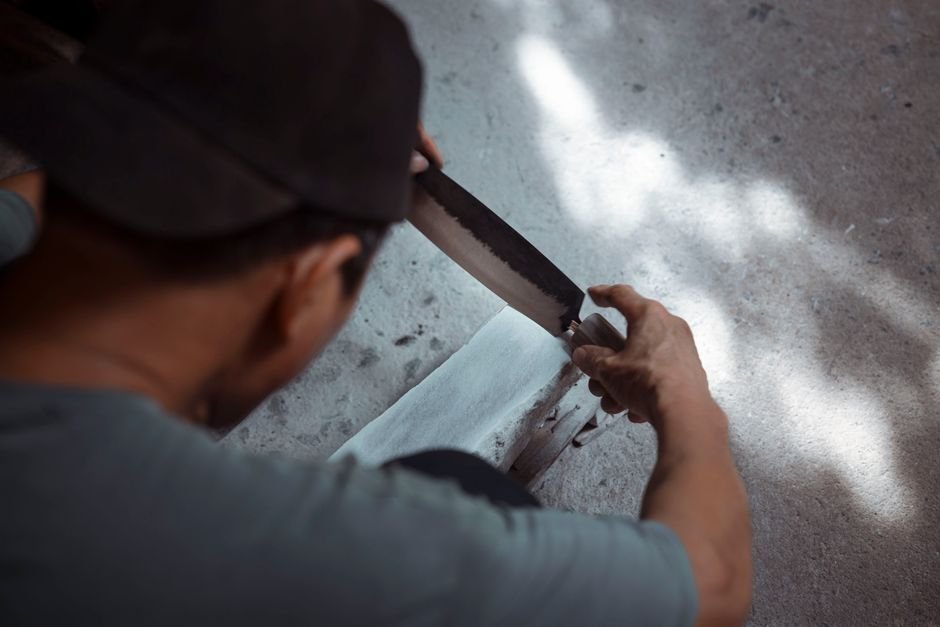 A person sharpening a knife on a whetstone in the traditional way