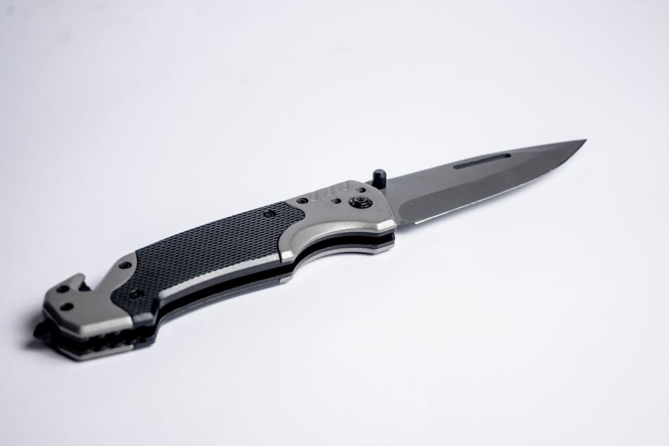 Tactical folding knife with a textured grip and bare metallic blade