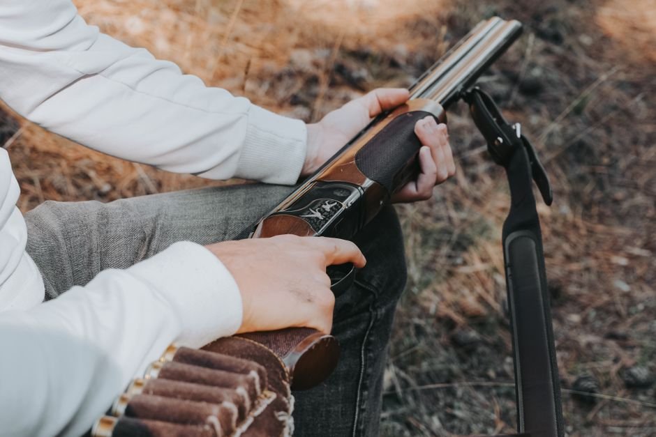 Close-up of a person loading a shotgun outdoors