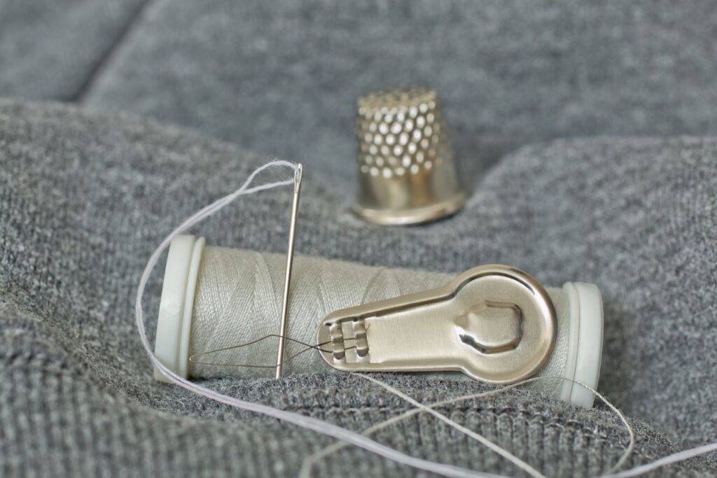 thimble needle and thread laid out for emergency repairs to pocket gear
