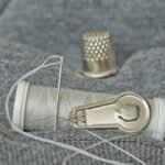 thimble needle and thread laid out for emergency repairs to pocket gear