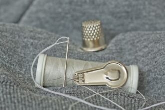 thimble needle and thread laid out for emergency repairs to pocket gear