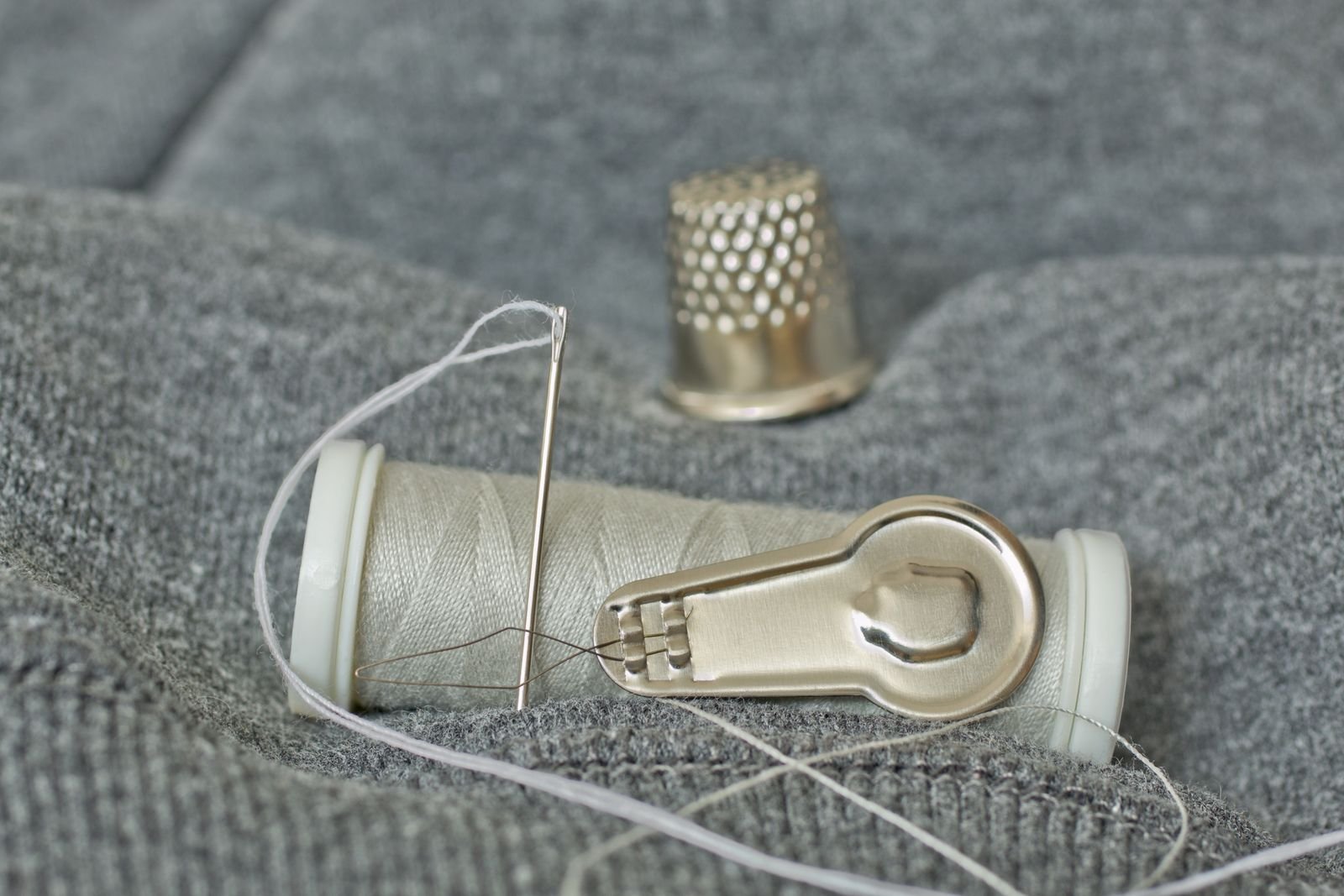 thimble needle and thread laid out for emergency repairs to pocket gear