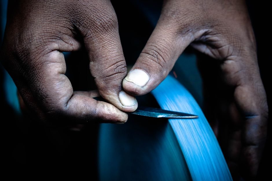 Close-up of hands holding a knife against a sharpening wheel