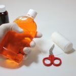 hand holding an antiseptic bottle alongside first aid supplies for cleaning a wound
