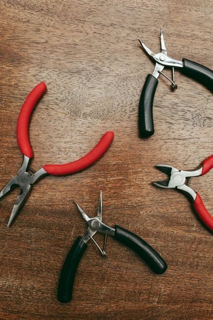 Several pairs of pliers arranged on a wooden surface, seen from above