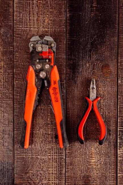 Wire strippers and pliers laid flat on a wooden surface