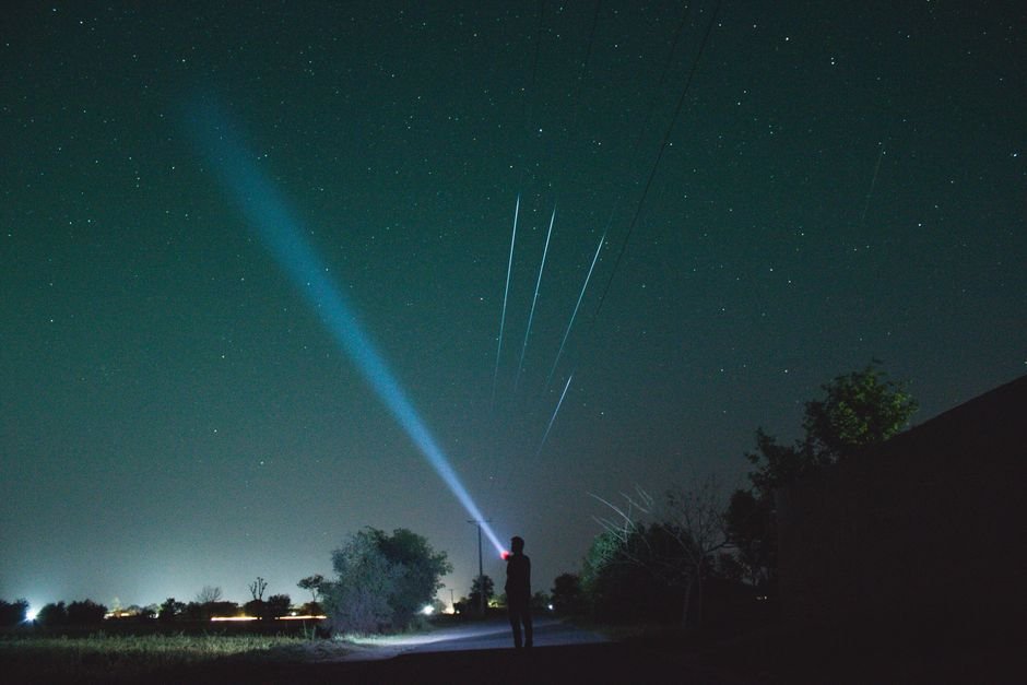 pexelsphoto7432769 edc deals person shining a bright edc flashlight beam into a starry night sky