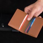 hand holding an open leather card holder with cards seated in its slots