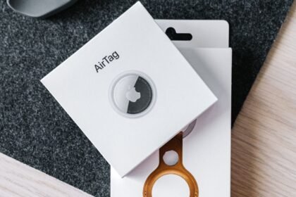 Apple AirTag and leather key ring packaging on a wooden surface