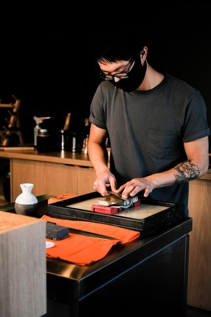 A chef sharpening a knife on a whetstone in a restaurant kitchen