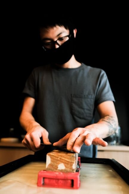 Close-up of hands sharpening a knife on a whetstone