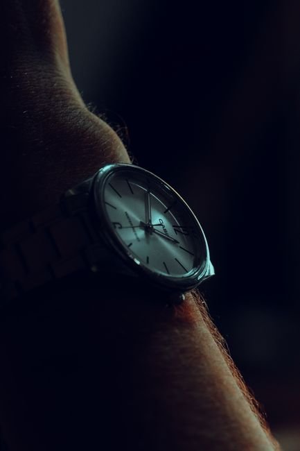 An analog wristwatch worn on the wrist against a dark background