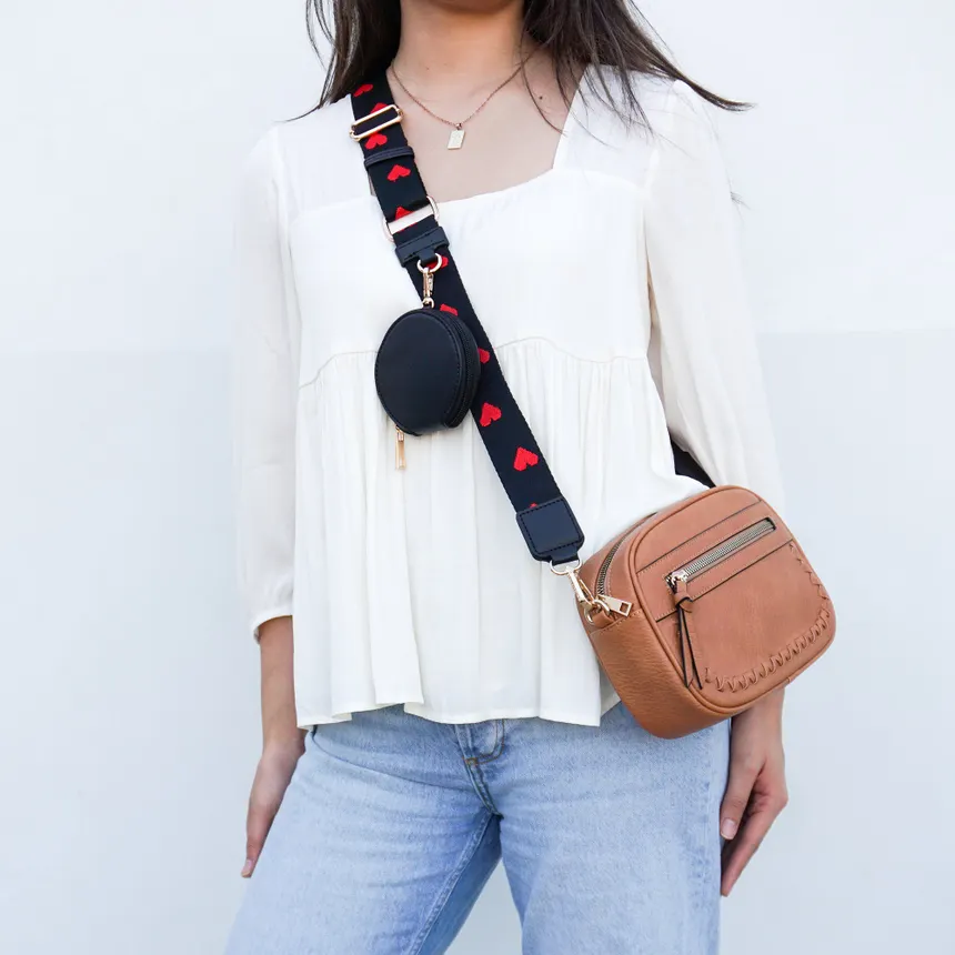 crossbody bag worn diagonally across white blouse also featuring a small black circular pouch attached to the strap