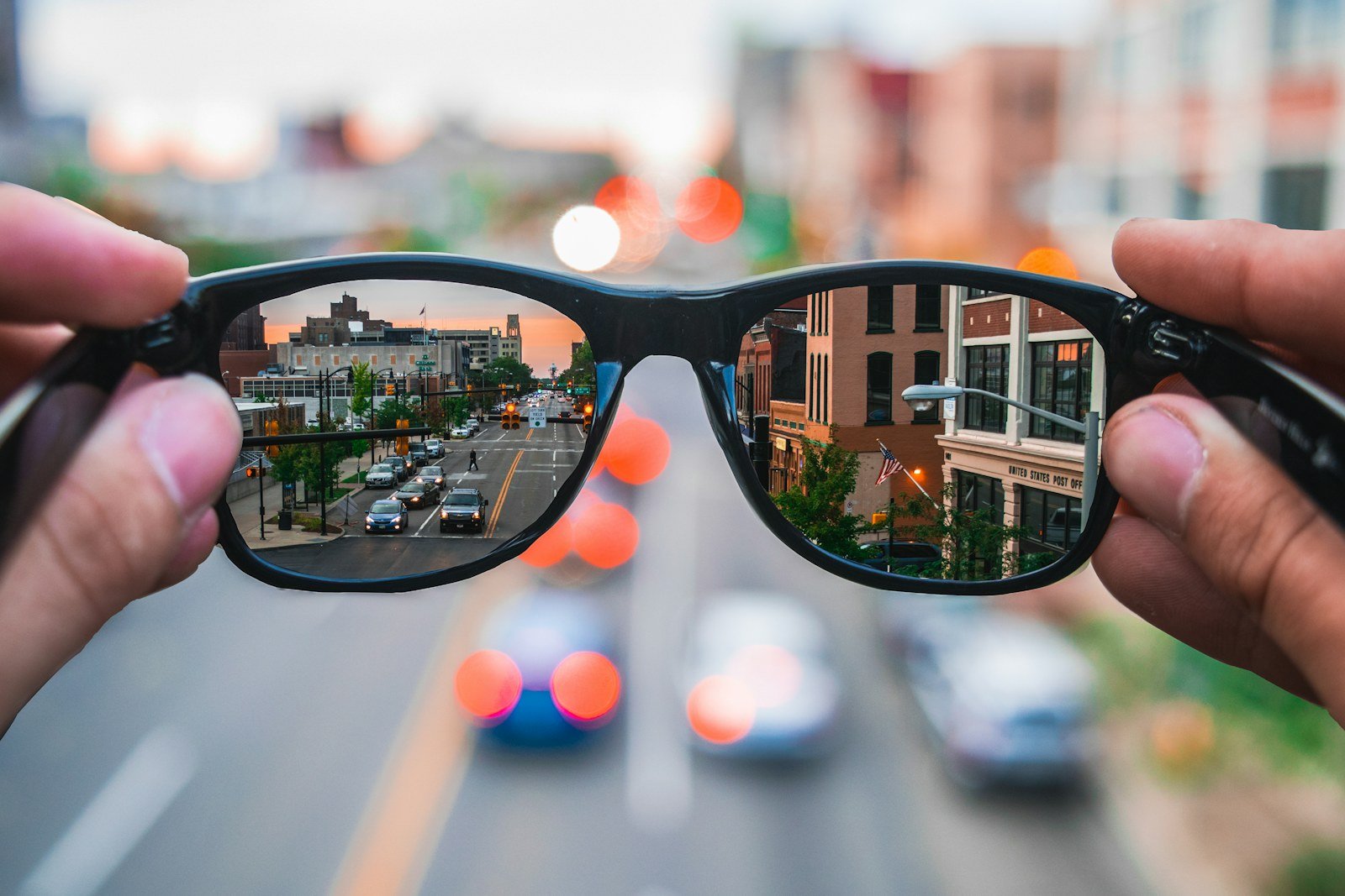 sunglasses reflecting a sunlit highway during a commute