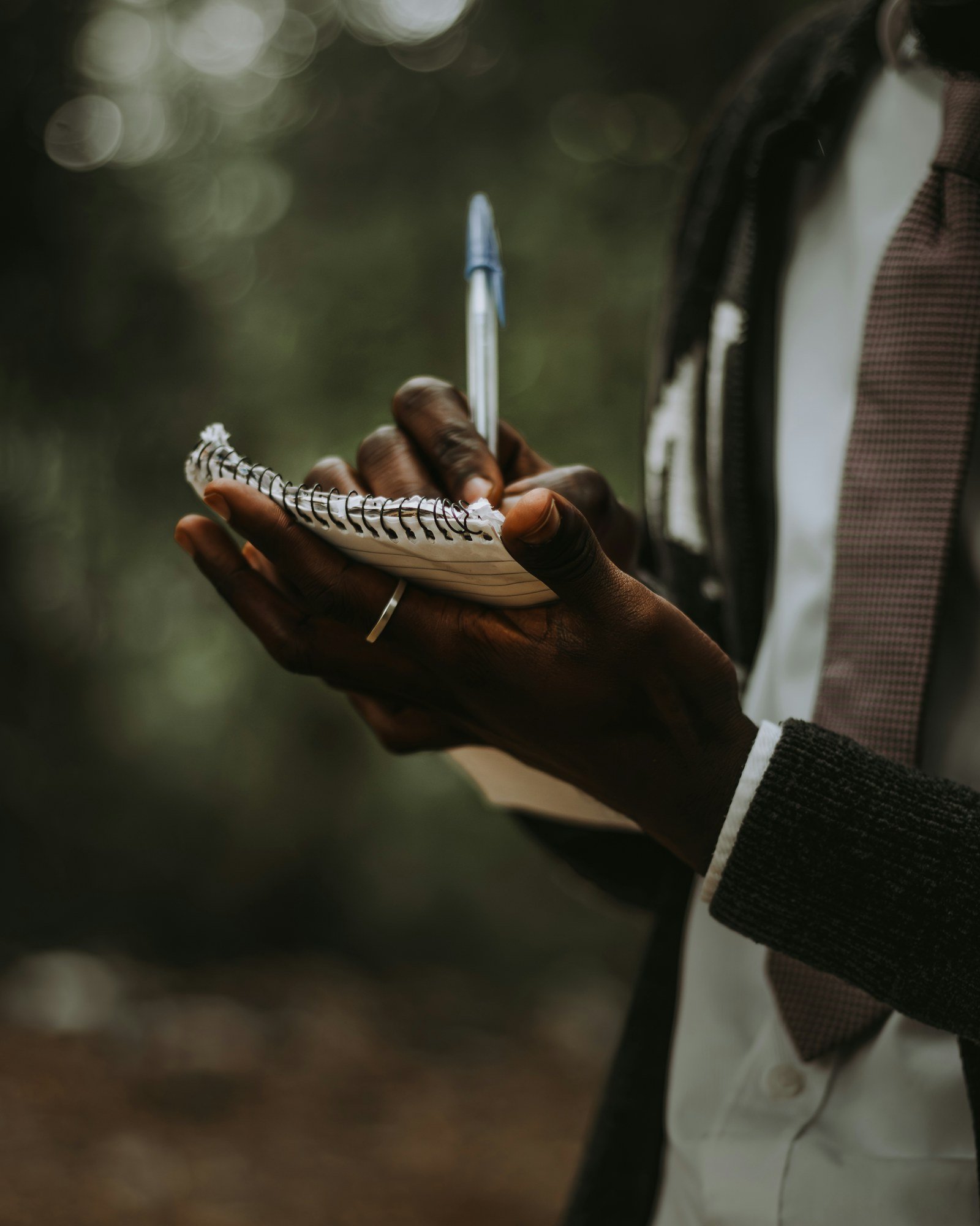 person writing notes in a notebook outdoors