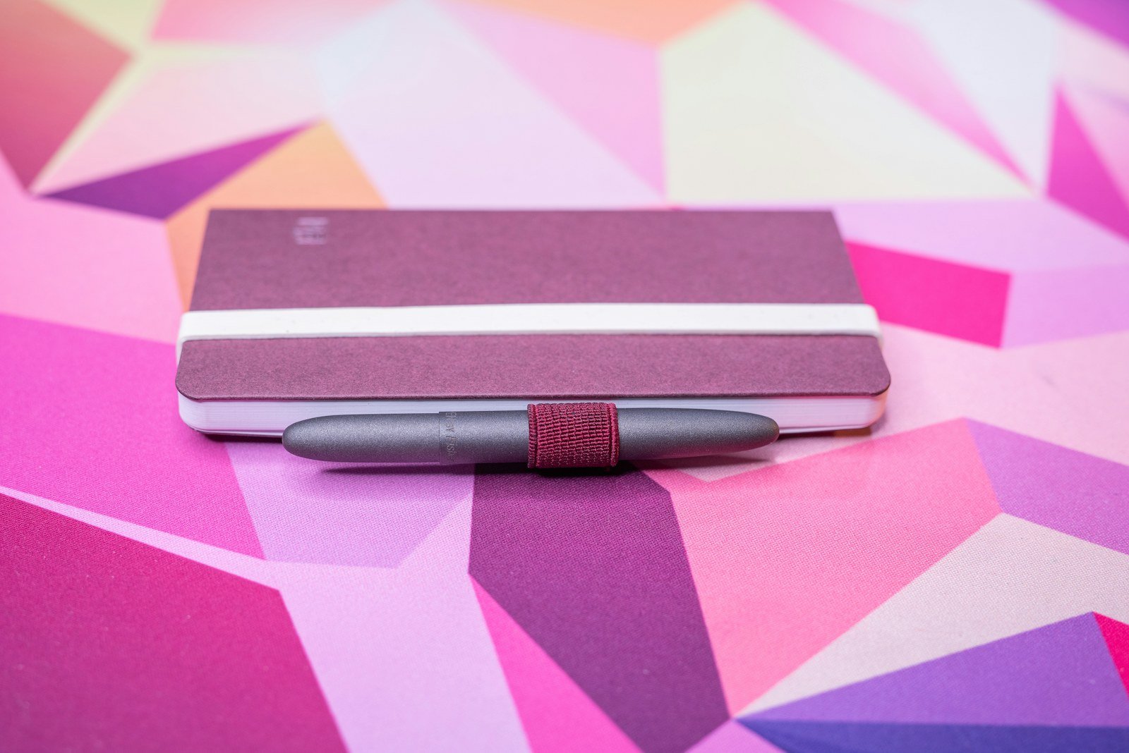 a fisher space pen bullet attached to a pocket notebook with a pen loop