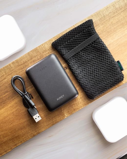 a coiled usb cable and power bank beside a small mesh cable pouch