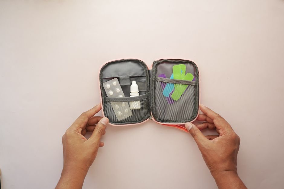 hands holding an open first aid kit with bandages and supplies