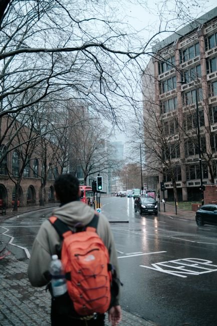 a person with a backpack walking on a rainy city street