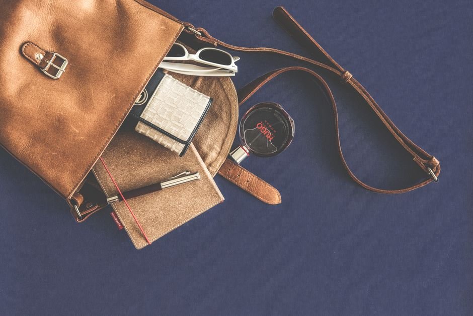 everyday carry essentials laid out next to a leather bag