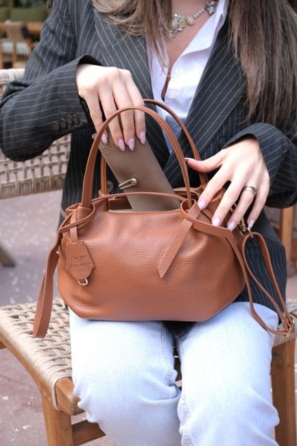 a woman reaching into her handbag and pulling out a small pouch