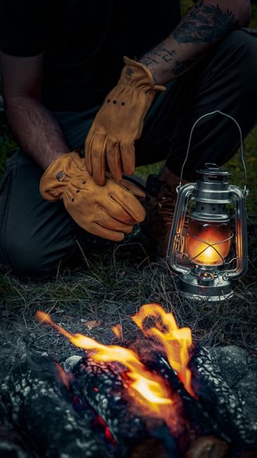 gloved hands tending a campfire