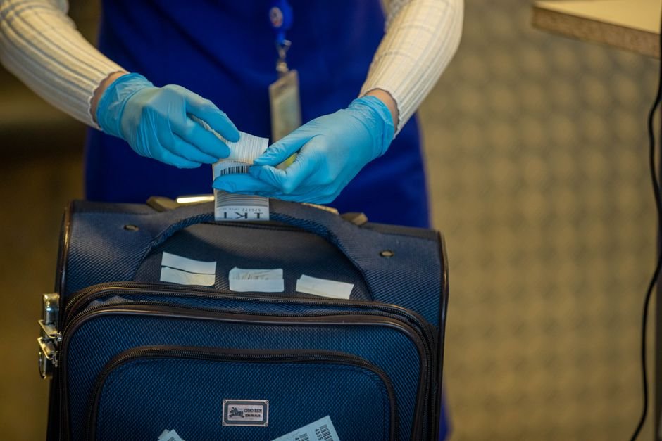 airport security officer inspecting checked luggage at a screening checkpoint