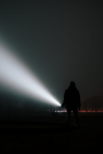 lumens vs candela comparison shown by a flashlight beam cutting through fog at night