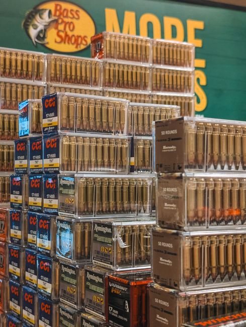 stacked ammunition boxes of various brands and quantities on a store shelf
