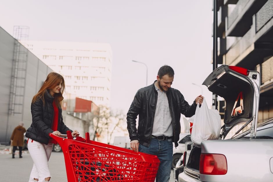 loading grocery bags from a shopping cart into a car trunk