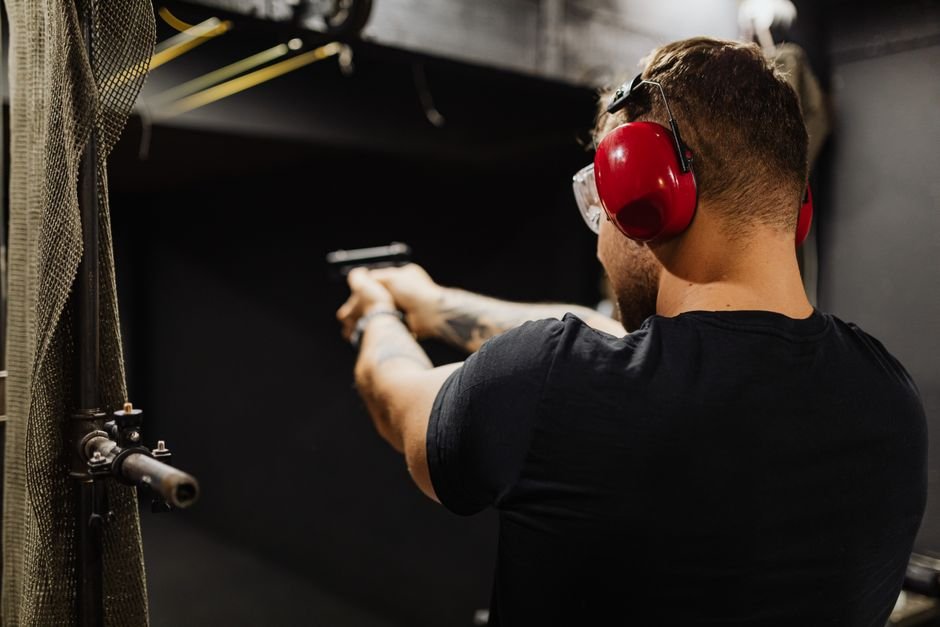 shooter wearing earmuffs and eye protection at an indoor firing range