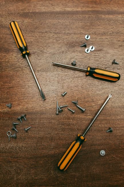 screwdrivers and assorted small screws on a wooden surface