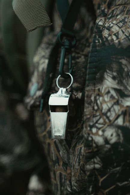 an emergency whistle hanging against camouflage fabric